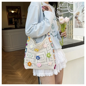 Detail of a handmade crochet tote bag with colorful 3D flowers and striped straps