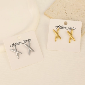 Close-up of gold and silver X-shaped stainless steel earrings on elegant display
