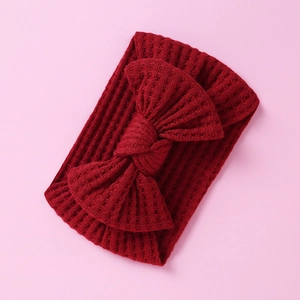 Close-up of red knitted waffle texture baby headband with a large decorative bow