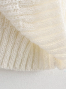 Gros plan des poignets en tricot côtelé blanc et de la texture douce de ce pull