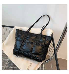 Detail of black quilted puffer tote bag with glossy nylon finish in a shopping basket