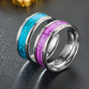 Macro shot of glow-in-the-dark heartbeat rings in blue and purple stainless steel