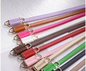 Detail showing a colorful collection of slim PU leather belts with gold metal buckles