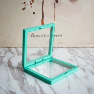 Detailed view of open mint green PE film floating jewelry box on marble surface