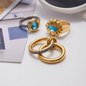 Detail of luxury gold and silver rings set with blue zircon gemstones and interlocking bands