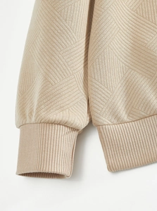 Macro detail of beige jacquard knit texture and ribbed cuffs on casual long sleeve shirt
