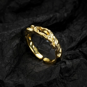 Minimalist gold lava texture open ring displayed on a dark wrinkled paper background