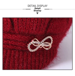 Detail showing red knitted wool texture with golden rhinestone bow buckle for winter hat