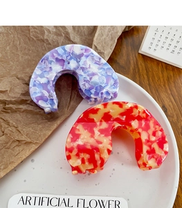 Détail de pinces à cheveux en acétate marbré violet et orange sur un décor de bureau chic