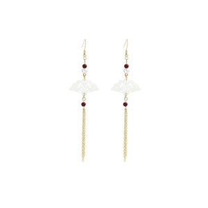 Detailed view of long gold tassel earrings with fan motifs and pearl bead accents