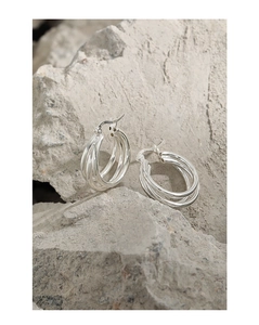 Macro shot of S925 sterling silver triple layer hoop earrings on a textured stone surface