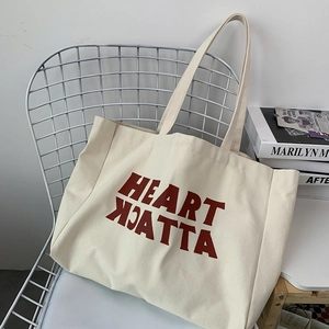 Detail of a large off-white canvas tote bag with Heart Attack print on a metal chair