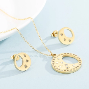 Détail de l'ensemble bijoux lune et étoile dorés avec strass sur fond bleu clair