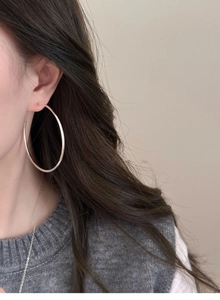 Close-up of minimalist silver C-shaped hoop earrings and delicate matching necklace