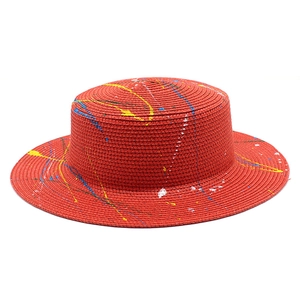 Detail of red flat-top straw hat featuring artistic colorful paint splatter graffiti