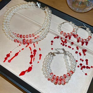 Detailed set of multi-strand pearl and red crystal bead jewelry in elegant display box