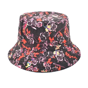 Détail d'un chapeau bob avec motifs de roses rouges et oiseaux jaunes sur fond noir