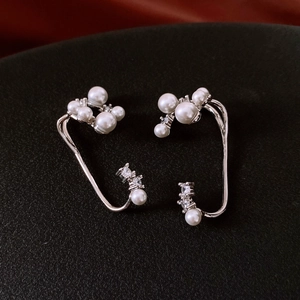 Detail of silver ear clips featuring white pearls and sparkling cubic zirconia stones
