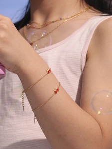 Détail d'un bracelet doré double rang avec trèfles émaillés rouges et blancs sur modèle