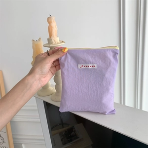 Macro detail of purple wrinkled fabric makeup bag with contrast yellow zipper and logo