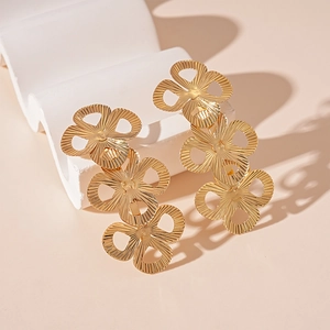 Detail of gold metal earrings featuring triple stacked heart-shaped flower pendants
