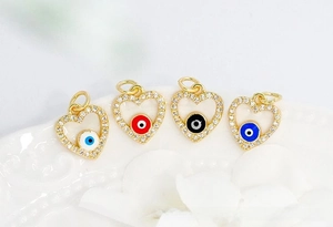 Macro detail of 18K gold plated heart evil eye charms with colorful enamel and zircon