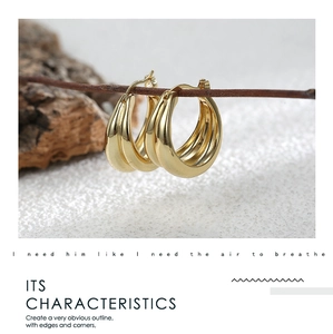 Macro detail of triple-layer gold earrings with polished mirror finish and sleek curves