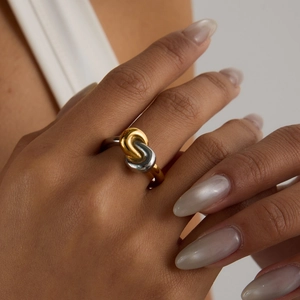 Close-up of interlocking gold and silver rings showing polished texture on a finger