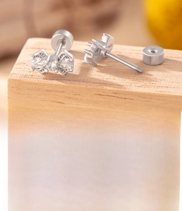 Detail view of silver bow-shaped titanium steel stud earring with cubic zirconia accents