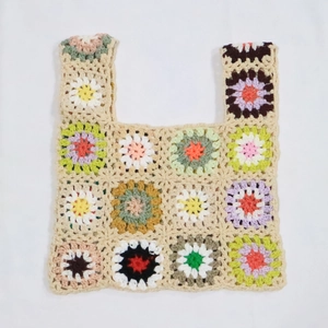 Close-up of handmade crochet tote bag featuring colorful granny square patterns and knit texture