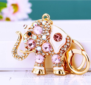 Macro shot of gold elephant keychain with sparkling pink and clear crystals on a book