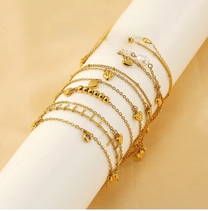 Close-up of gold 18K titanium steel bracelets with pearls and heart charms on a stand