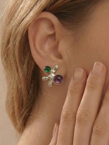 Détail macro de boucles d'oreilles géométriques avec pierres vertes et violettes