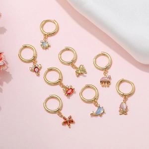Gold ocean themed earrings with colorful charms like crab and starfish on pink background
