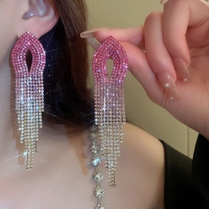 Detail showing elegant long pink gradient rhinestone tassel earrings on a model