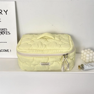 Close-up of light yellow cloud quilted cosmetic bag with heart pattern and ribbon zipper