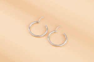 Detailed close-up of polished silver stainless steel hoop earrings with snap closure
