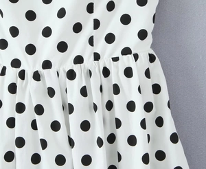 Macro detail of white polka dot fabric with elegant waist pleats and smocked texture