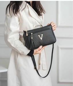 Chic black women's shoulder bag with gold V logo, tassel decor, and practical zipper design.