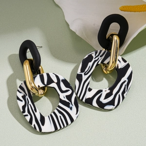 Detail view of acrylic geometric earrings with zebra stripes and gold metal ring link