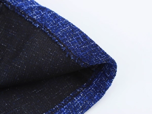 Close-up of blue and black tweed fabric texture showing woven patterns and hem stitching