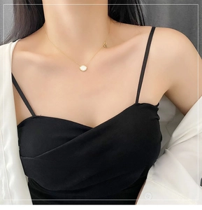 Close-up of a gold titanium steel shell necklace worn by a model for a fashion look
