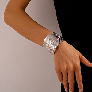 Macro detail of silver feather cuff bracelet showing realistic metallic texture and wide design