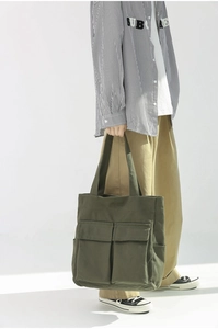 Detail of army green canvas tote bag featuring double front pockets and large capacity
