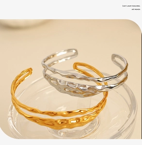 Detail of gold and silver open bangles with irregular texture on glass surface