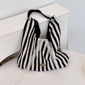 Détail du sac cabas en toile rayée avec bordure en dentelle et logo en métal doré