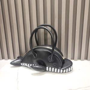 Detail of creative black whale-shaped handbag featuring striped base and golden zippers