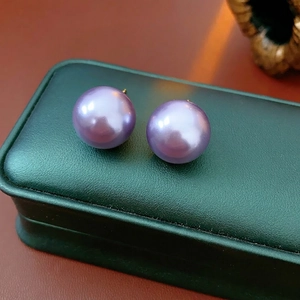 Elegant 10-12mm purple pearl earrings with gold-plated pins on a dark green jewelry box