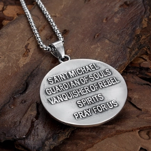 Detail shot of St. Michael pendant with engraved prayer text on a wooden surface