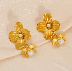 Detail of gold floral pearl drop earrings showcasing intricate petals on champagne silk